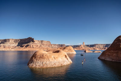 Rock formations in sea against clear blue sky