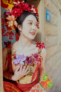 Portrait of young woman standing against wall