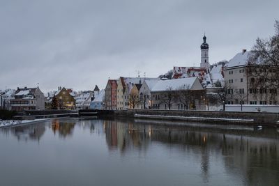 Buildings by river against sky