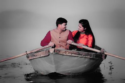 Smiling man and woman boating on lake during foggy weather