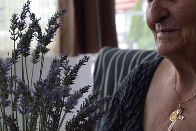 Midsection of smiling senior woman with lavenders at home