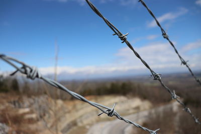 Close-up of barbed wire fence against sky