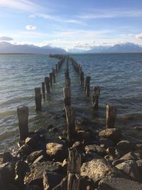 Wooden posts in sea against sky