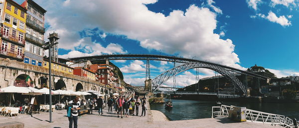 People on bridge against cloudy sky