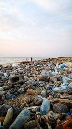 Plastic bottles and rocks at beach against sky