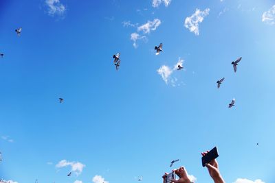 Low angle view of people flying against sky