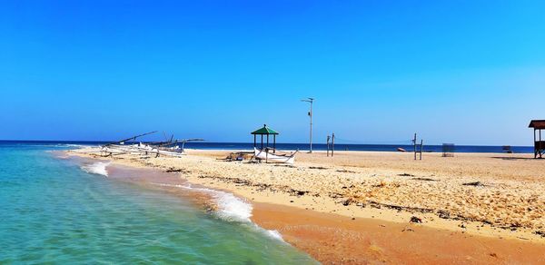 Scenic view of beach against clear blue sky