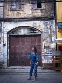 Woman looking away standing against door of building