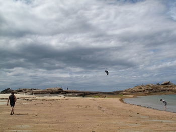 People at beach against cloudy sky