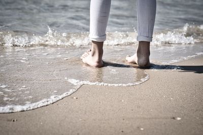 Low section of man standing on beach