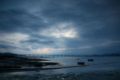 Boats moored at beach against cloudy sky