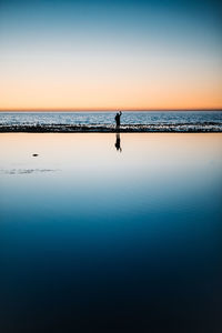 Silhouette person on beach against sky during sunset