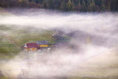 Spring landscape. traditional mountain village on hills. rural sunrise. smoke house. clouds of fog