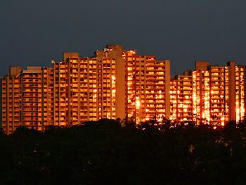 Illuminated buildings against clear sky at night