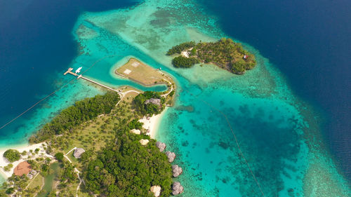 Malipano island with a sandy beach and azure water surrounded by a coral reef and an atoll.