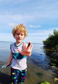 Boy standing in water against sky