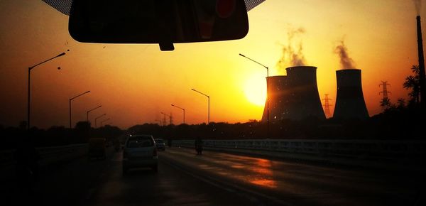 Cars on road against sky during sunset