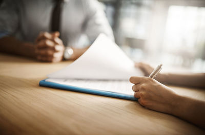 Midsection of woman writing in book