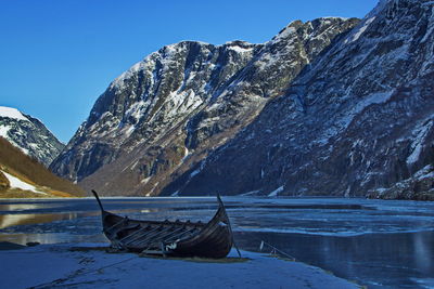 Boat moored at lakeshore against mountain