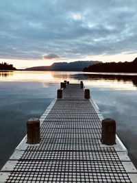 Pier on lake against sky during sunset