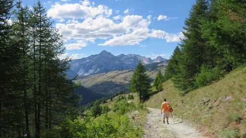 Rear view of person walking on mountain against sky