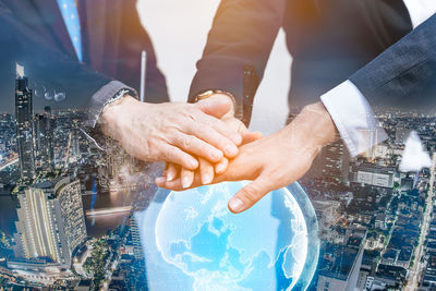 Midsection of man holding hands with cityscape in background