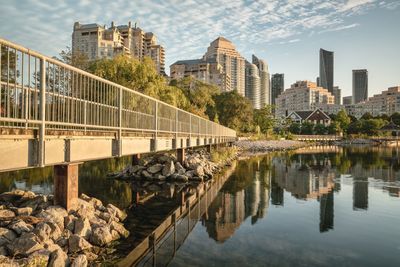 Bridge over river by buildings against sky