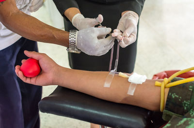 Midsection of doctors taking blood from patient in hospital