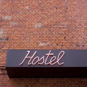 Low angle view of neon hostel sign on brick wall