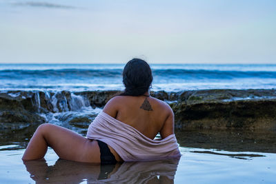 Rear view of woman swimming in sea against sky