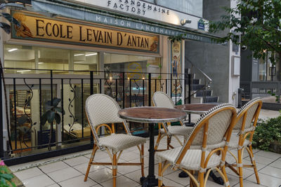 Empty chairs and tables at sidewalk cafe against buildings