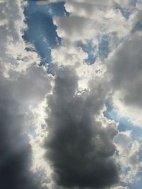 Low angle view of sunlight streaming through clouds