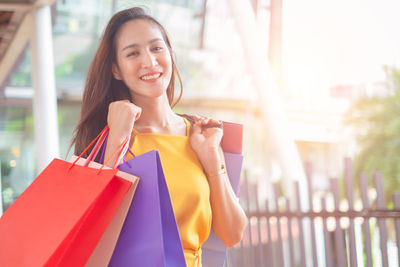 Portrait of a smiling young woman holding store