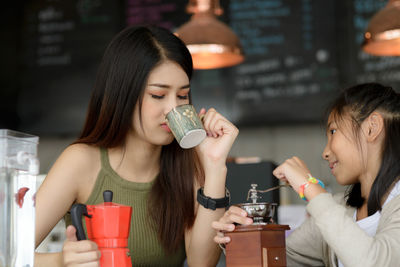 Female owner with girl drinking coffee at cafe