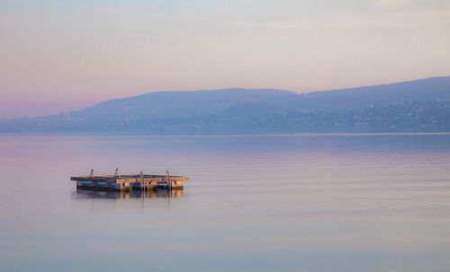 Boat in sea against sky during sunset