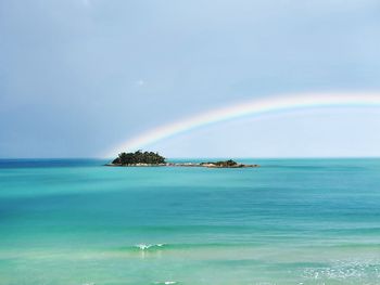 Scenic view of sea against rainbow in sky