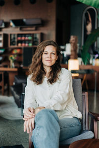 Portrait of young woman sitting on sofa at home