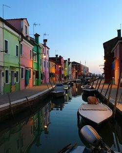 Boats moored in canal by buildings against sky