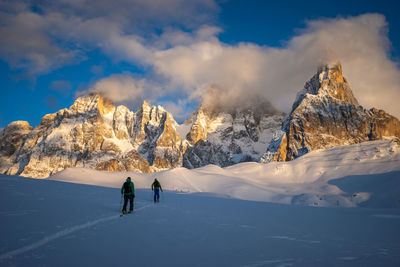 Rear view of people on snowcapped mountain against sky