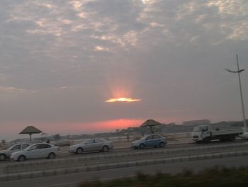 Cars on street against sky during sunset