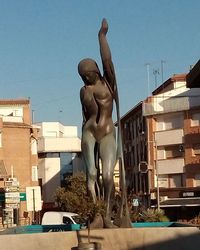 Low angle view of statue by swimming pool against buildings