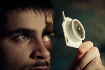 Close-up of young man's eyes holding a magnifying glass 