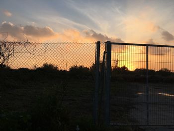 Chainlink fence on field at sunset