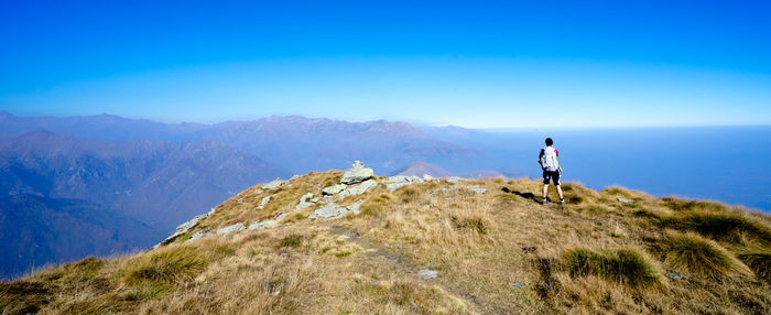 Rear view of man standing on mountain against clear sky