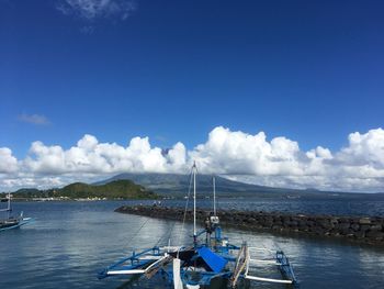 Boats moored on sea against blue sky