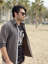 Young man looking away while standing in park