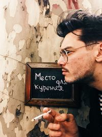 Portrait of young man holding text on wall