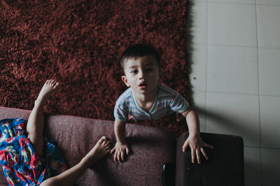 Portrait of baby boy by sofa at home