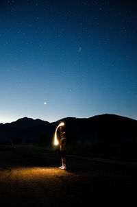 Young man standing on land against sky at night