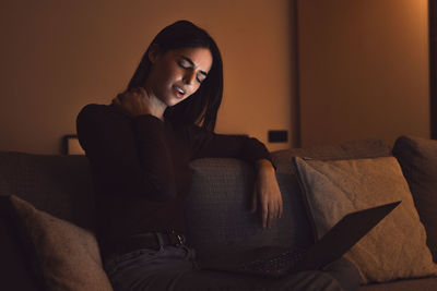 Young woman sitting on sofa at home